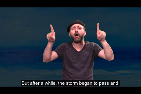 A white man with a mustache and beard signed FINALLY in ASL. He is wearing a cap and a dark grey shirt and appears against a dark blue background. The captions at the bottom of the screen say :But after a while, the storm began to pass and".